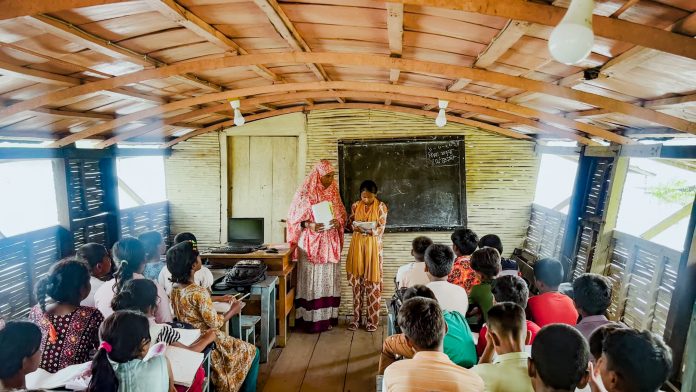 Hosne Ara teaches a group of fourth graders, seated on benches inside the floating school