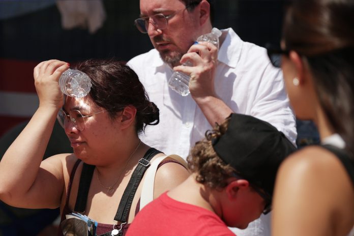 People cool themselves with an ice-cold water bottle from a water station during the Great American State Fair on the National Mall on July 2, 2026 in Washington, DC.
