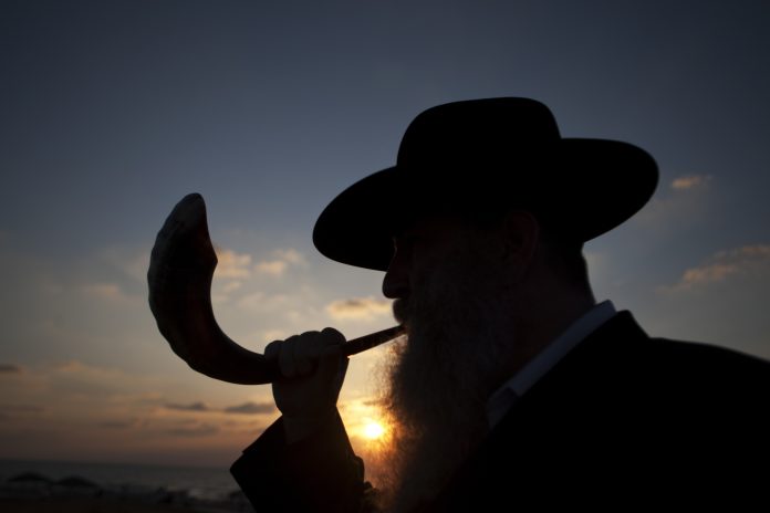 A man blows a shofar, or ram