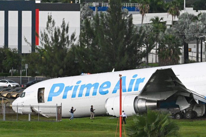 Officials investigate a Prime Air cargo plane at Miami International Airport after it overran the runway at Miami International Airport in Miami, Fla., on Sept. 6, 2026. An Amazon cargo plane overshot a runway as it landed in Miami, crashing into vehicles and catching fire, officials said.