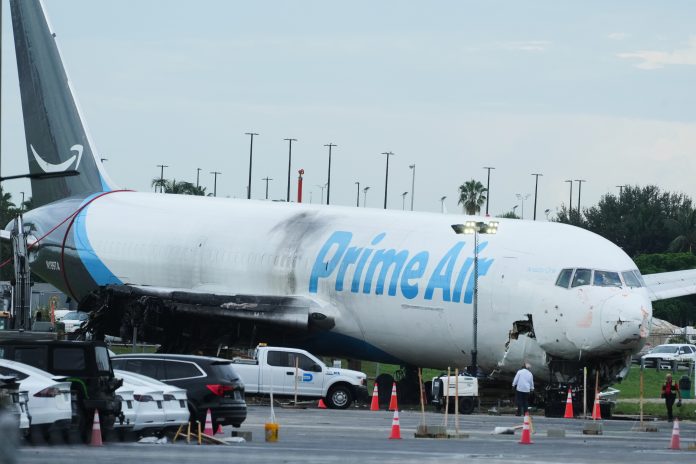 Workers inspect an Amazon cargo plane that overshot a runway four days ago at Miami International Airport, Thursday, Sept. 10, 2026, in Miami.