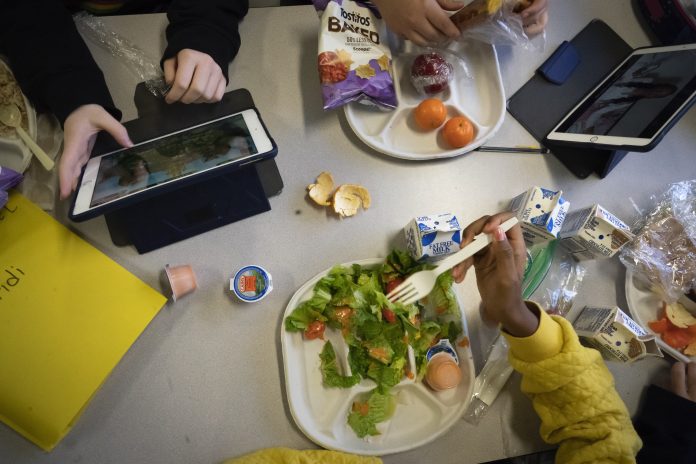 Seventh-graders sit together in the cafeteria during their lunch break at a public school in Brooklyn, N.Y., on Feb. 10, 2023.