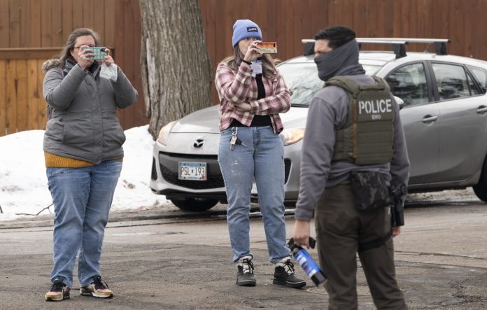 Observers film ICE agents in Minneapolis in February. A new lawsuit alleges that the federal government is trying to intimidate observers who monitor immigration enforcement operations.