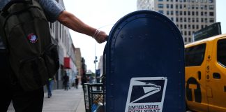 Mail-in voters weigh flying to vote in person and other backup plans amid uncertainty A person drops mail into a blue U.S. Postal Service collection box in New York City in 2020.
