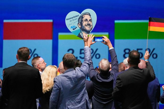 AfD supporters celebrate with a sign featuring top candidate Ulrich Siegmund after the first results of the Saxony-Anhalt state election at the party