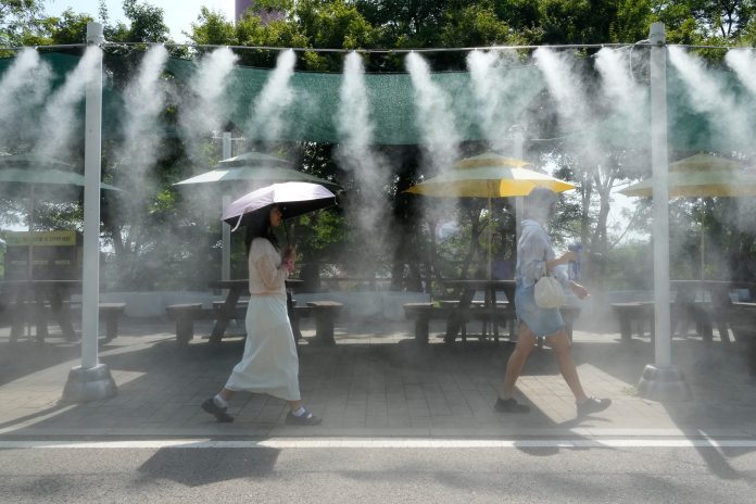 Visitors pass by the cooling fog device at Gwangmyeong Cave tourist site in Gwangmyeong, South Korea, Aug. 6, 2026.