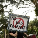Voters are fed up with data centers. Both parties are trying to cash in for midterms A person holds signs during a nationwide protest against AI data center expansion in New Port Richey, Florida on July 18, 2026.